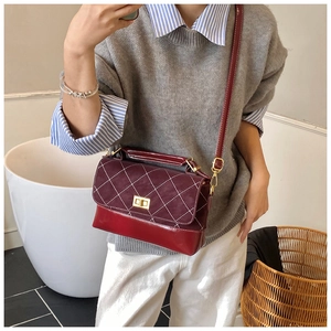 Close-up of burgundy quilted crossbody bag with gold twist lock on person