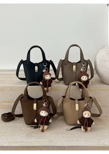 Sacs seaux en cuir grainé de quatre couleurs avec breloques d'ours sur marbre