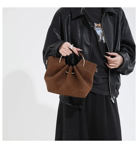 Detail of vintage brown suede shoulder bag featuring a unique gold metal ring handle