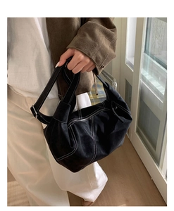 Detail shot of black dumpling bag featuring contrast white stitching and metal zipper