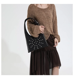 Détail d'un sac à main en daim noir avec rivets métalliques argentés au style punk chic