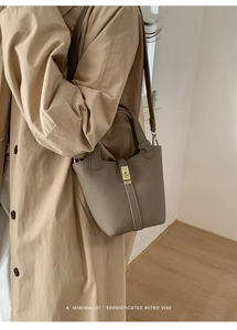 Detail of lychee pattern bucket bag with gold lock shown on model in trench coat