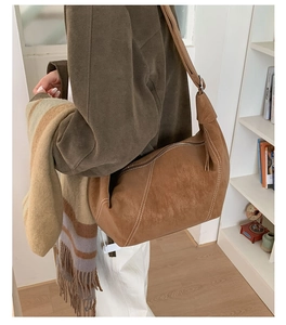 Detail of dark brown suede shoulder bag with contrast white stitching and long strap