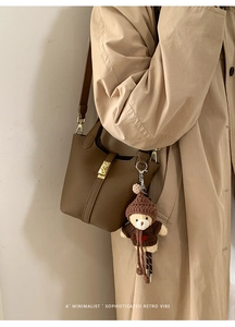 Detail of brown pebbled leather bucket bag with gold lock and cute bear charm