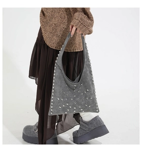 Detail of grey suede tote bag with decorative silver rivets and bohemiam punk design