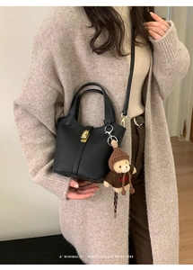 Détail du sac seau en cuir grainé noir avec fermoir doré et pendentif ours en peluche