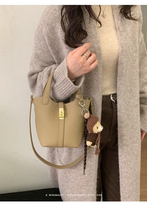 Détail du sac seau kaki avec texture grainée, fermoir doré et pendentif ours