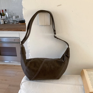 Détail du sac demi-lune marron foncé avec surpiqûres blanches et bandoulière réglable