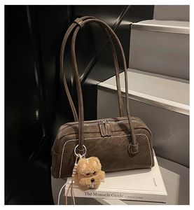 Detail of brown matte underarm bag with contrast stitching and small puppy plush charm