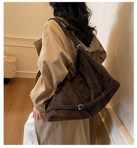 Detail of large brown suede tote bag featuring contrast stitching and adjustable silver buckle
