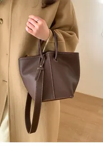 Detail of a brown lychee pattern leather bucket bag with contrast white stitching