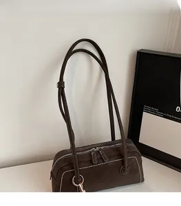 Detail of dark brown Boston bag with contrast white stitching and silver hardware