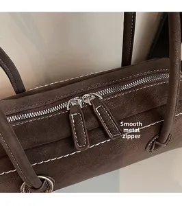 Detail of premium brown suede underarm bag with dual smooth zippers and metal hardware