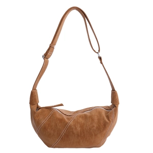 Brown leather crescent crossbody bag with white contrast stitching and adjustable strap
