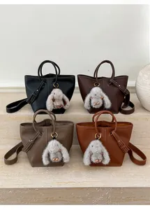 Detail of four colorful leather bucket bags with plush rabbit charms on stone steps