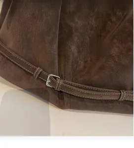 Detail of dark brown suede tote bag featuring white contrast stitching and silver metal buckle