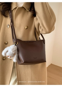 Detail of dark brown lychee leather bucket bag with shoulder strap and plush bunny charm