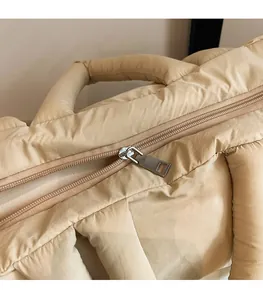 Detail of smooth metal zipper and quilted fabric on a beige puffer tote bag