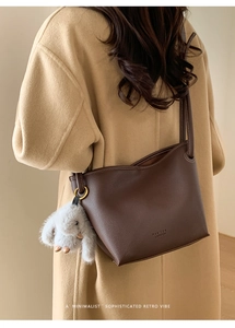 Detail of dark brown pebble leather bag with gold hardware and white plush bunny charm