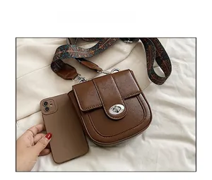 Brown saddle bag with vintage jacquard strap compared to phone for scale