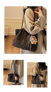 Detail of dark brown tote bag with white contrast stitching and plush dog charm accessory