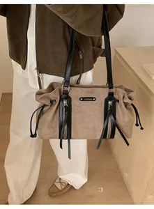 Detail of suede tote bag featuring brown patchwork, dual zippers and long tassels