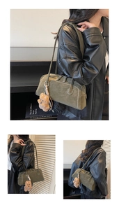 Detail of dark green pillow shoulder bag with white contrast stitching and plush bear charm