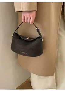 Detail of dark brown leather crescent bag with gold buckle on wool coat background
