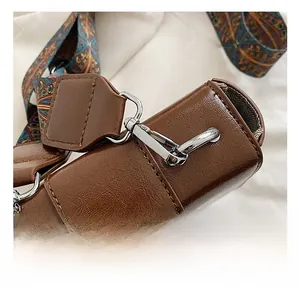 Macro detail of brown saddle bag side hardware and vintage floral pattern strap