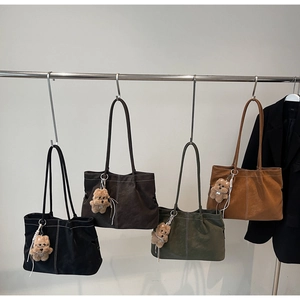 Detail of four large tote bags in matte texture with contrast stitching and plush bear charm