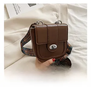 Close-up of brown PU leather saddle bag with silver twist lock and ethnic style strap