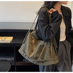 Detail of olive green slouchy tote bag featuring pleated faux suede texture and strap