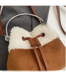 Detail of plush lamb wool and suede bucket bag showing drawstring closure and metal handle