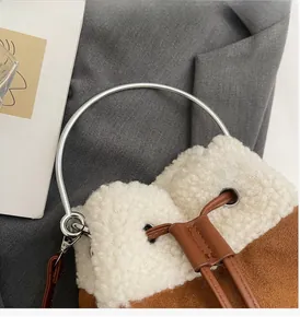 Detail view of plush bucket bag featuring silver metal ring handle and drawstring closure