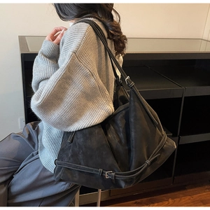 Detail view of large black hobo tote bag featuring white contrast stitching and buckle