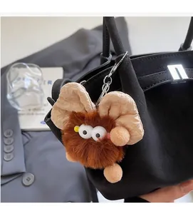 Makroaufnahme eines braunen Plüschmonster-Schlüsselanhängers an einer schwarzen Tasche