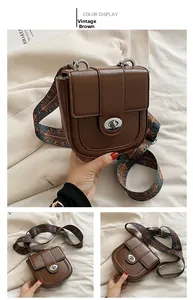 Detail of vintage brown saddle bag with stylish floral print wide shoulder strap