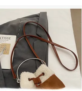 Detail of suede bucket bag with shearling trim, silver metal ring handle and leather strap
