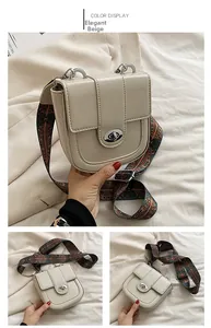 Detail of elegant beige saddle bag featuring a stylish ethnic pattern wide strap and oval lock