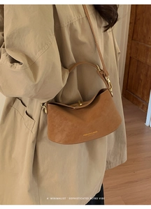 Detail of minimalist brown leather underarm bag with gold lettering and adjustable strap