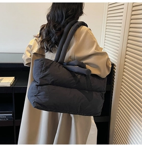 Close-up of black quilted puffer tote bag on shoulder for daily autumn commute