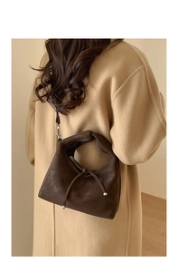Deep brown shoulder bag with knotted handle and silver ball detail on autumn coat