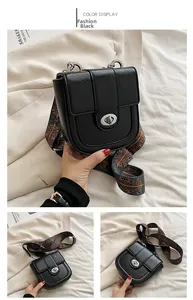 Detail of black leather saddle bag with silver twist lock and colorful woven strap