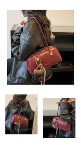Detalle del bolso de hombro de cuero burdeos con cremallera dorada y mini accesorio