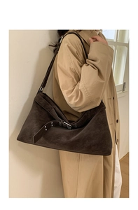 Detail of dark brown suede tote bag with adjustable buckle and eyelet strap decoration