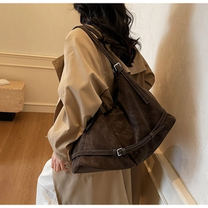Detail of adjustable silver buckle and straps on a large coffee brown suede tote bag