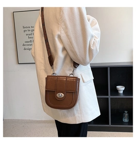 Detail of vintage brown saddle bag showing glossy PU leather texture and wide strap