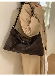 Detail of a large coffee suede tote bag with metal buckle on a beige trench coat