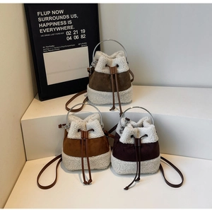 Three plush faux fur bucket bags in brown and caramel shades on a white minimalist pedestal