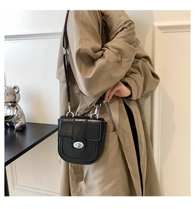 Detail showing the black vintage leather saddle bag worn with a khaki trench coat